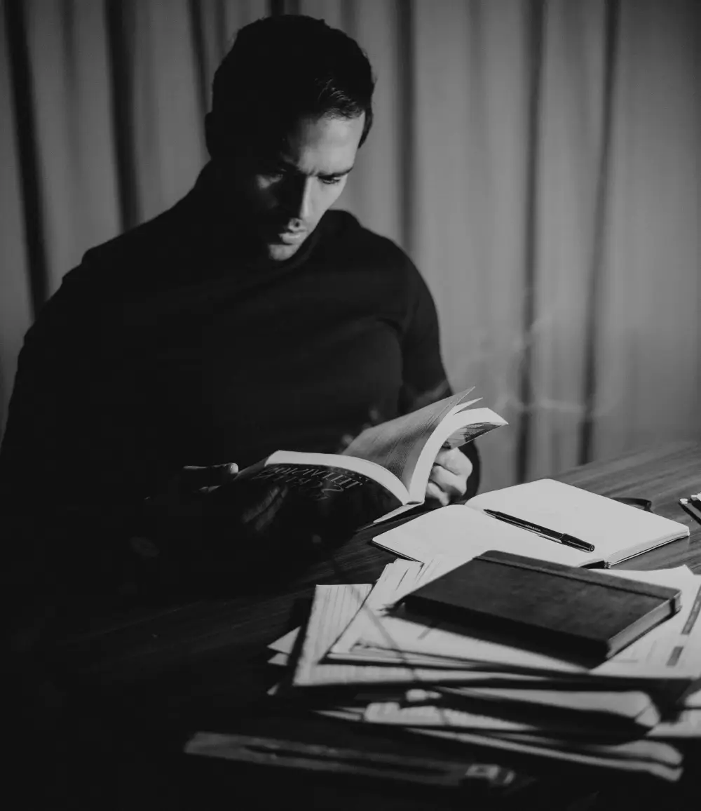 A man sitting at a table reading a book.